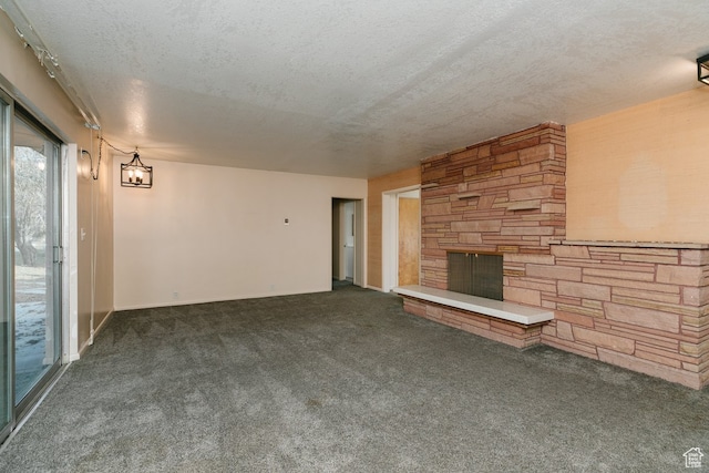unfurnished living room featuring a fireplace, a textured ceiling, and dark carpet