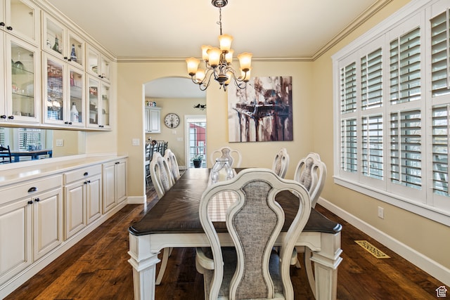 dining room featuring dark hardwood / wood-style flooring, ornamental molding, and an inviting chandelier