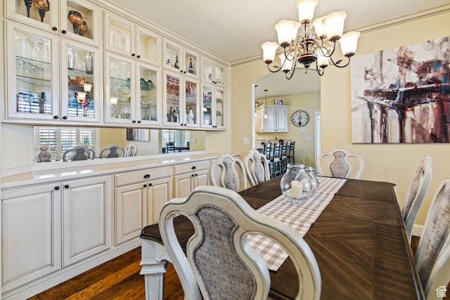dining area with a notable chandelier, dark hardwood / wood-style flooring, and ornamental molding