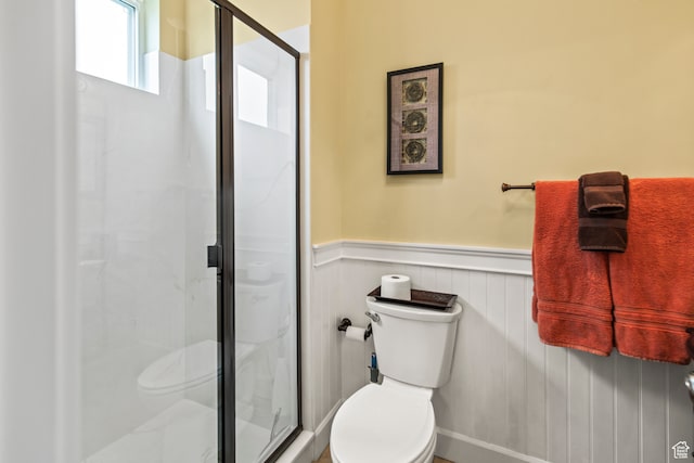 bathroom with a shower with shower door and toilet