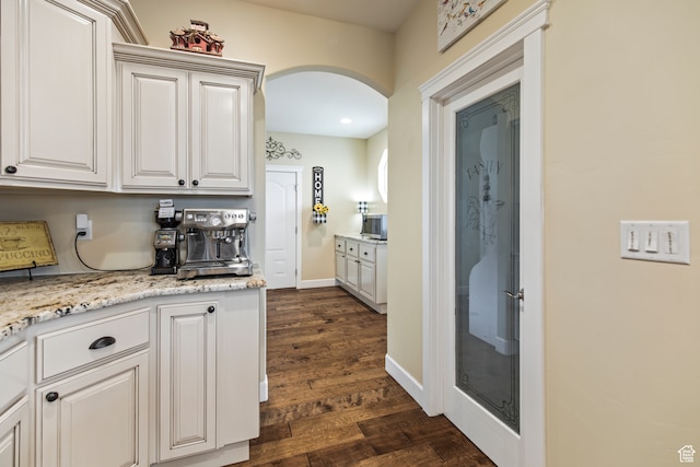 kitchen featuring light stone counters, dark hardwood / wood-style flooring, and white cabinets