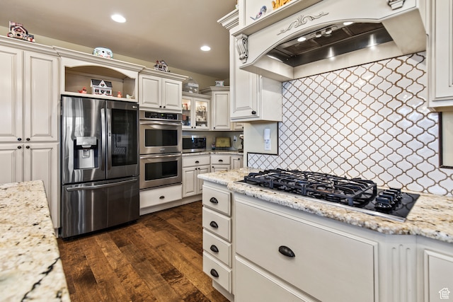 kitchen with light stone countertops, range hood, dark hardwood / wood-style flooring, white cabinetry, and stainless steel appliances