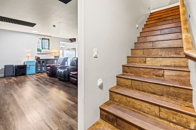 stairway with wood-type flooring and bar