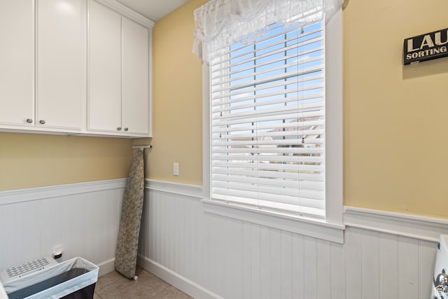 clothes washing area with plenty of natural light, cabinets, and light tile patterned floors