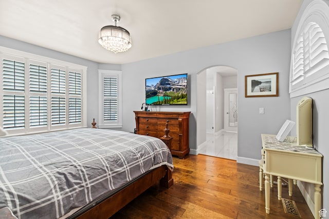 bedroom with wood-type flooring and an inviting chandelier