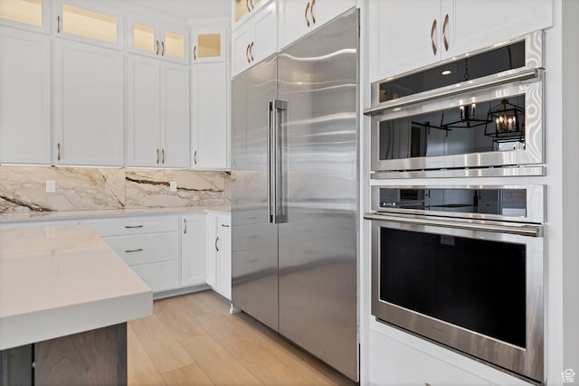 3092 E 2110th St S, St George, UT 84790 - kitchen featuring appliances with stainless steel finishes, light countertops, white cabinets, light wood-type flooring, and glass insert cabinets