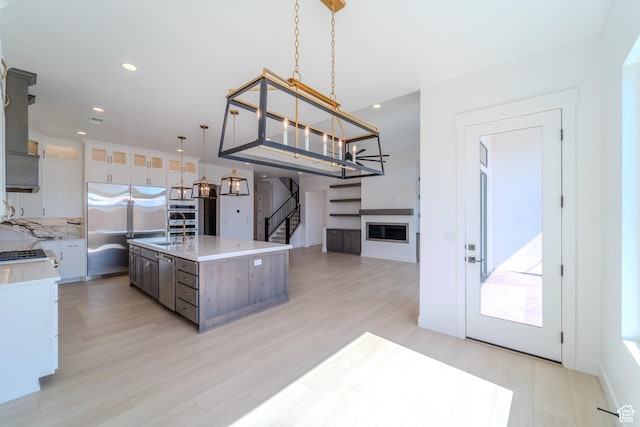 3092 E 2110th St S, St George, UT 84790 - kitchen with appliances with stainless steel finishes, light countertops, a chandelier, a glass covered fireplace, and light wood-style flooring