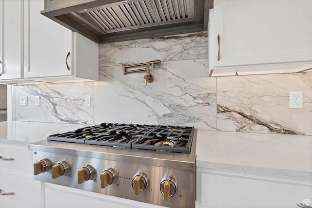 3092 E 2110th St S, St George, UT 84790 - kitchen view of stainless steel gas cooktop, premium range hood, backsplash, white cabinetry, and pot filler
