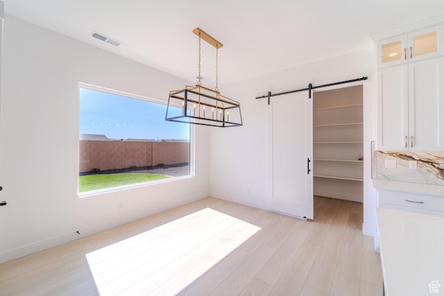 3092 E 2110th St S, St George, UT 84790 - unfurnished dining area with a barn door, light wood-style flooring, a chandelier, and baseboards