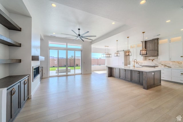 3092 E 2110th St S, St George, UT 84790 - kitchen with custom range hood, recessed lighting, light wood finished floors, a glass covered fireplace, and a sink