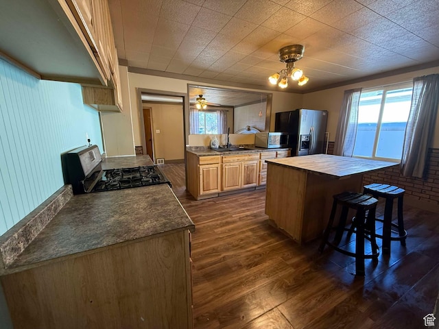 kitchen with dark hardwood / wood-style floors, sink, a breakfast bar area, stainless steel appliances, and light brown cabinets