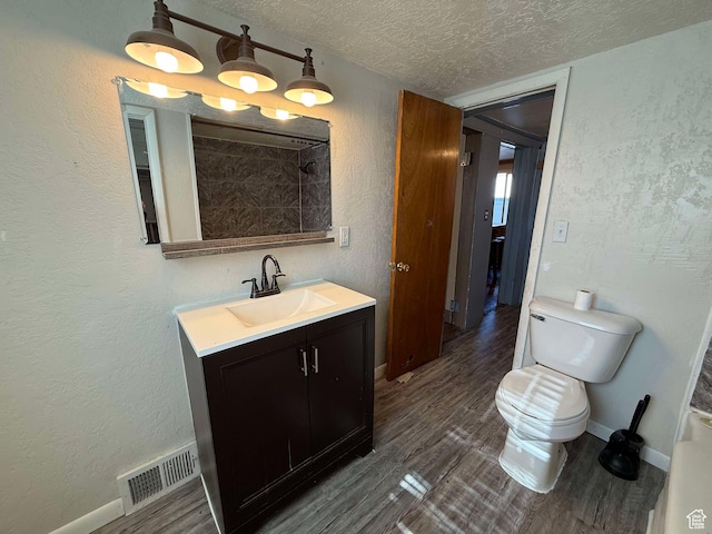 bathroom with vanity, toilet, hardwood / wood-style floors, and a textured ceiling