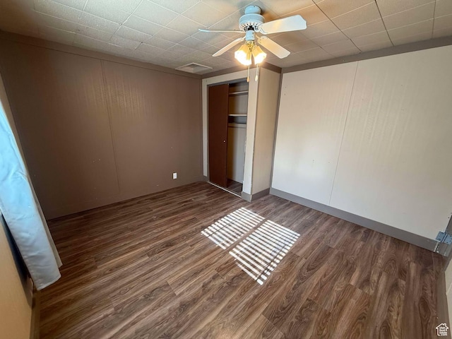 unfurnished bedroom featuring dark hardwood / wood-style flooring, a closet, and ceiling fan