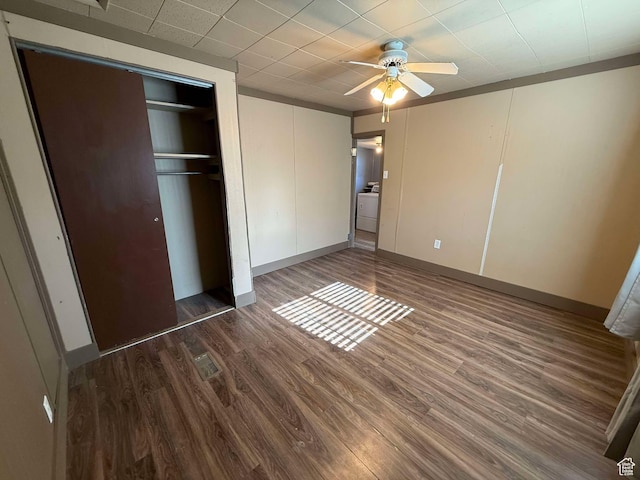 unfurnished bedroom with washer / dryer, dark wood-type flooring, a closet, and ceiling fan