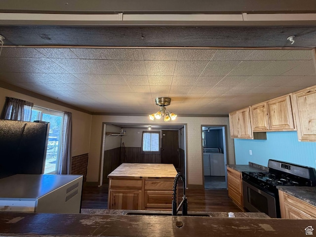 kitchen featuring sink, light brown cabinets, dark hardwood / wood-style floors, stainless steel range with gas stovetop, and washing machine and dryer