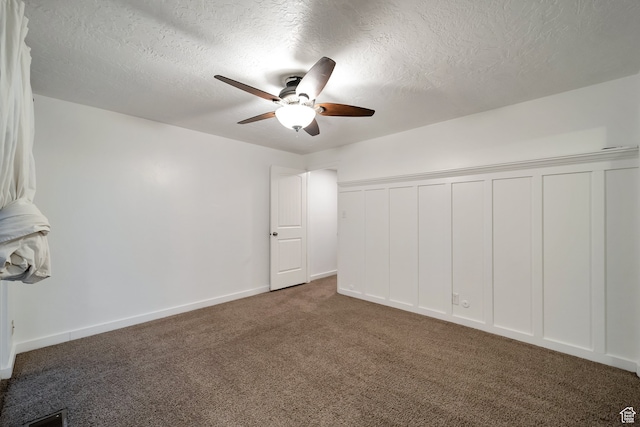 interior space with dark colored carpet, ceiling fan, and a textured ceiling