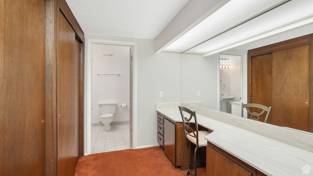 bathroom featuring toilet, a textured ceiling, vanity, baseboards, and tile patterned floors