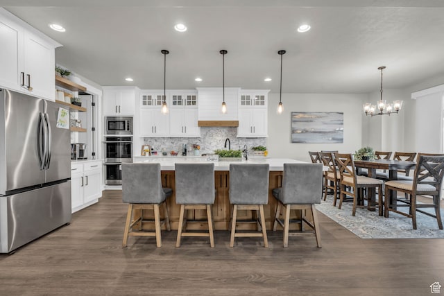 kitchen featuring appliances with stainless steel finishes, dark hardwood / wood-style floors, white cabinetry, and a kitchen island with sink