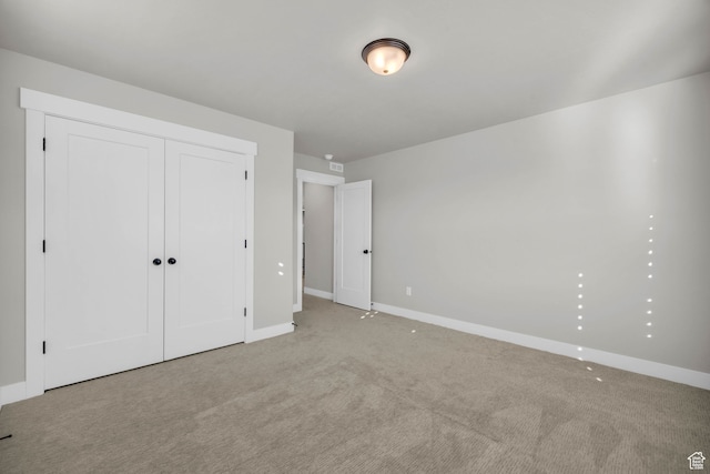unfurnished bedroom with light colored carpet and a closet