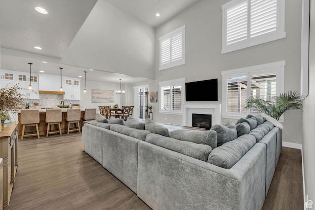 living room with a healthy amount of sunlight, dark hardwood / wood-style flooring, and a towering ceiling