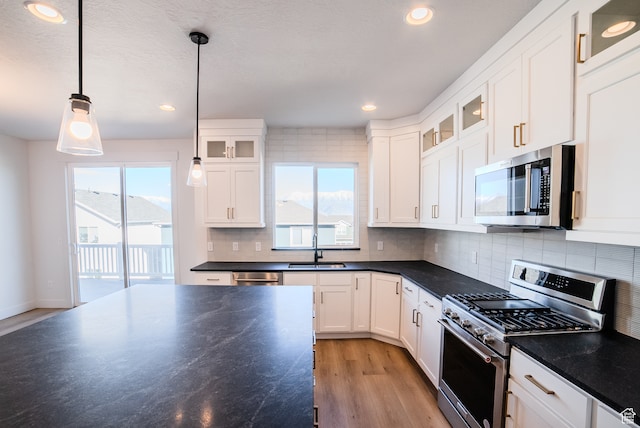 kitchen with plenty of natural light, white cabinetry, stainless steel appliances, and hanging light fixtures