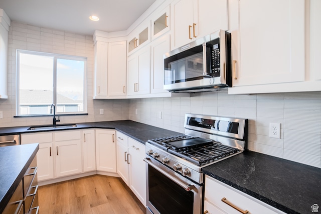 kitchen with white cabinets, sink, tasteful backsplash, light hardwood / wood-style floors, and stainless steel appliances