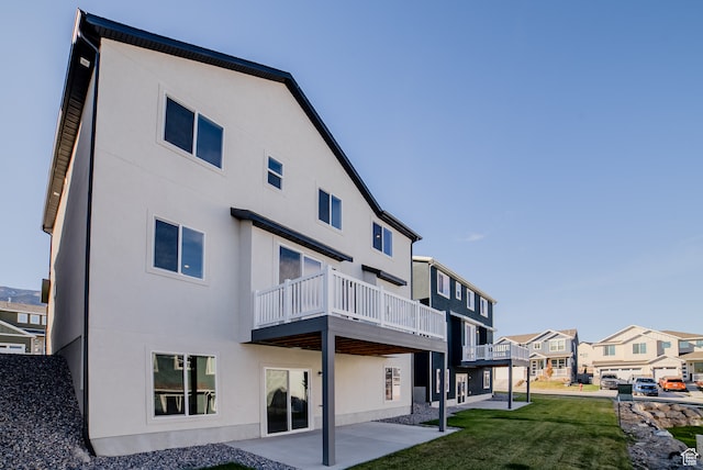 back of property featuring a balcony, a yard, and a patio