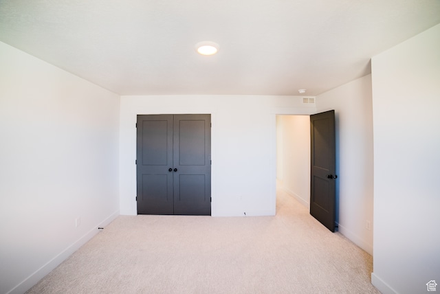 unfurnished bedroom featuring light colored carpet and a closet