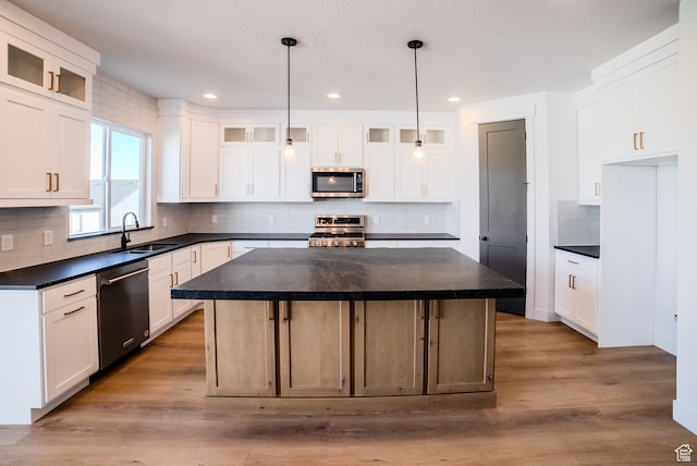 kitchen featuring white cabinetry, sink, hanging light fixtures, stainless steel appliances, and a kitchen island
