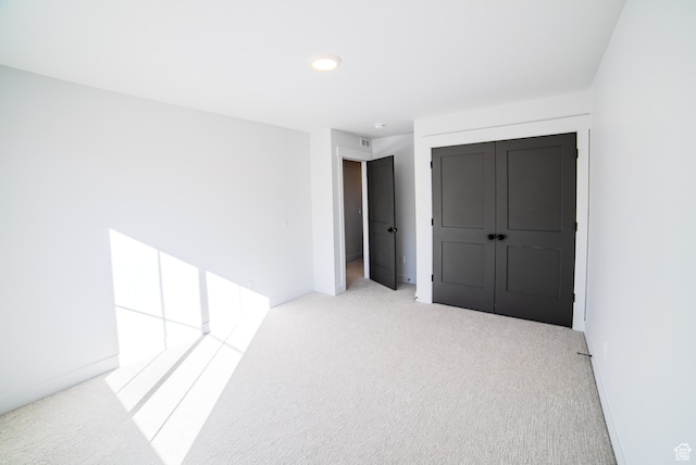 unfurnished bedroom with light carpet and a closet