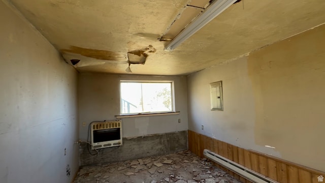 miscellaneous room with electric panel, heating unit, a baseboard radiator, and wooden walls