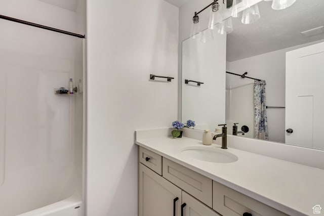 bathroom featuring shower / bath combo with shower curtain, vanity, and a textured ceiling