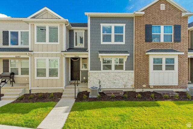 townhome / multi-family property with a front yard and central AC unit