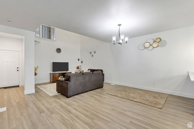 living room featuring a chandelier, light hardwood / wood-style floors, and a textured ceiling