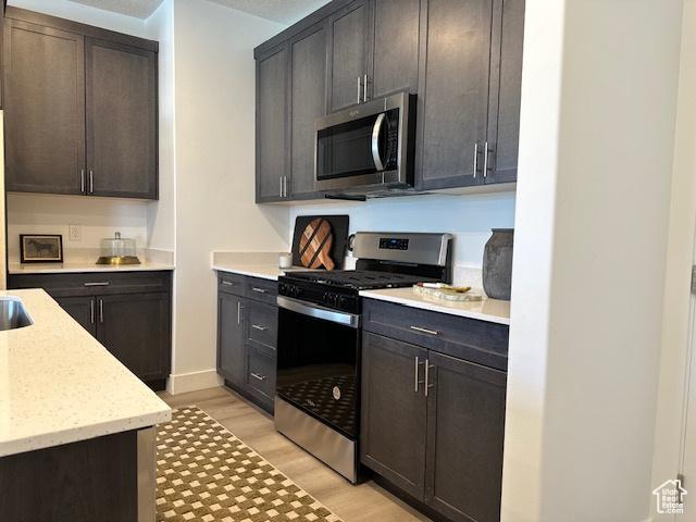 1044 E 1930 S Unit 419, Heber City, UT 84032 - kitchen featuring appliances with stainless steel finishes, light wood-type flooring, light stone counters, and dark brown cabinets
