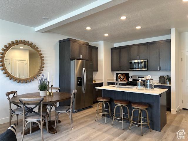 1044 E 1930 S Unit 419, Heber City, UT 84032 - kitchen featuring stainless steel appliances, a textured ceiling, light wood-style floors, light countertops, and a breakfast bar area