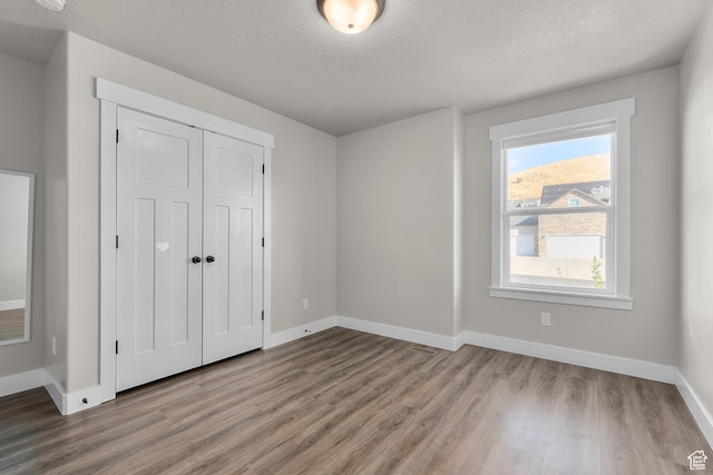 2388 E Horizon Dr Unit 907, Eagle Mountain, UT 84005 - unfurnished bedroom with wood finished floors, baseboards, a closet, and a textured ceiling
