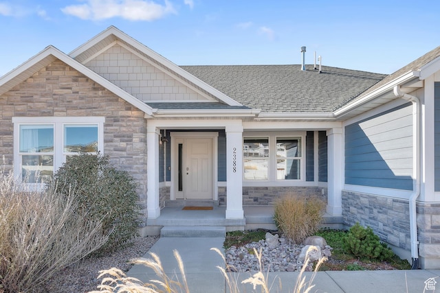 2388 E Horizon Dr Unit 907, Eagle Mountain, UT 84005 - view of exterior entry with stone siding, a shingled roof, and covered porch