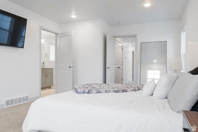 carpeted bedroom featuring ensuite bath