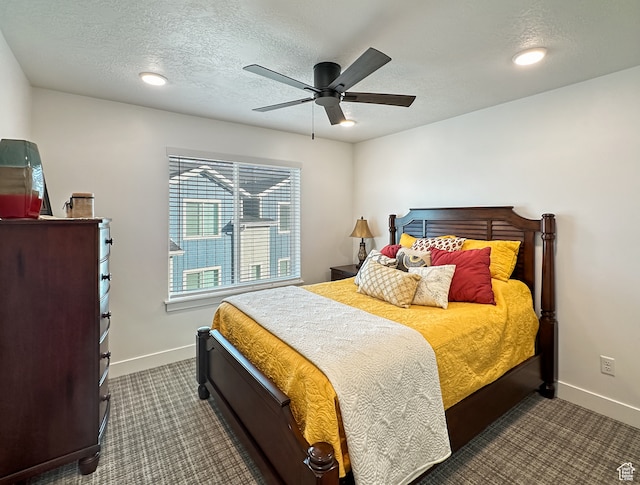 bedroom featuring a textured ceiling, dark carpet, and ceiling fan