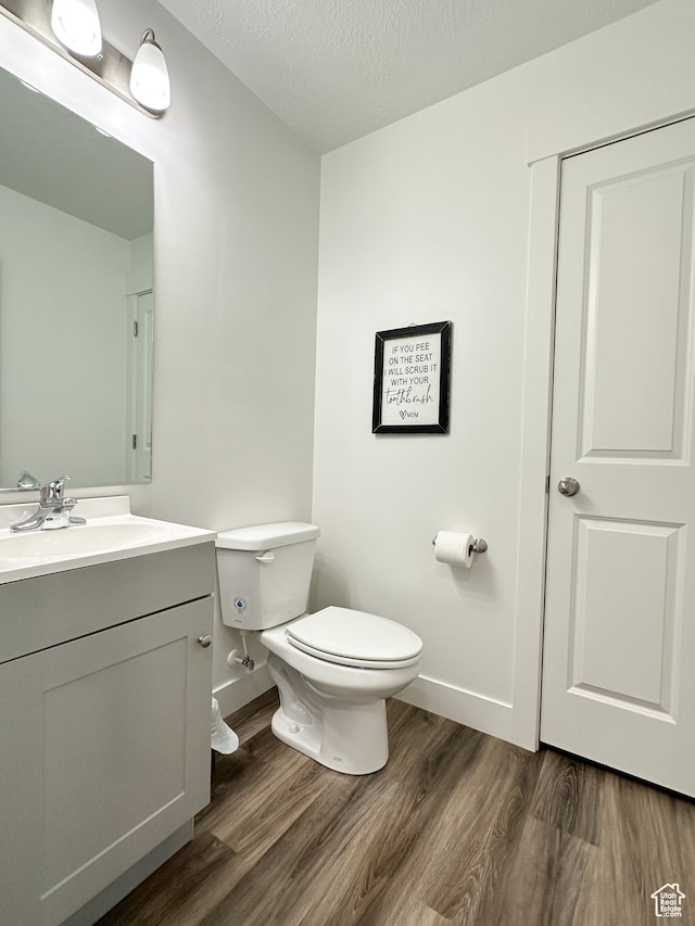 bathroom featuring vanity, wood-type flooring, a textured ceiling, and toilet