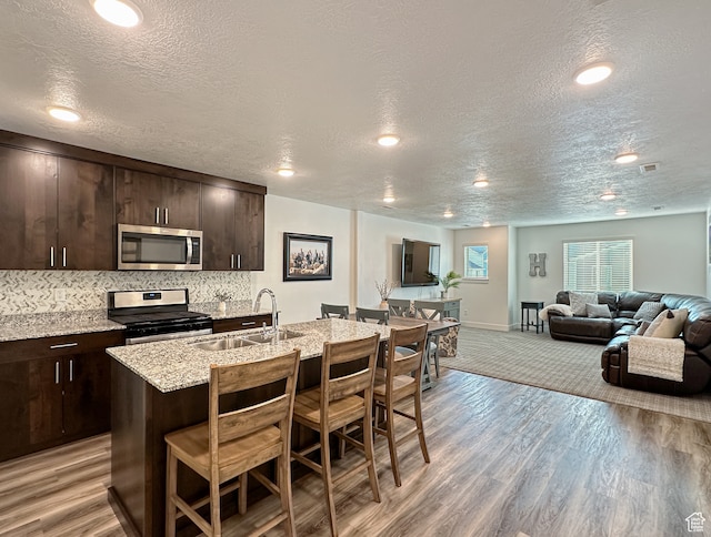 kitchen with light wood-type flooring, appliances with stainless steel finishes, a textured ceiling, and sink