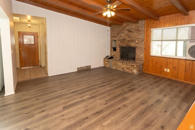 215 N 300 W, Salina, UT 84654 - unfurnished living room featuring a wood ceiling with exposed beams, ceiling fan, wood finished floors, wood walls, and a brick fireplace