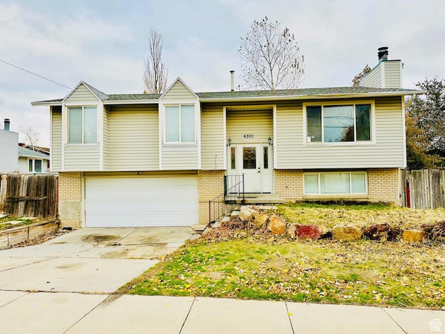 6301 S 2700 W, Taylorsville, UT 84129 - split foyer home featuring brick siding, a garage, a chimney, and concrete driveway