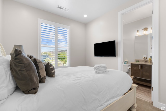 bedroom featuring light hardwood / wood-style floors and ensuite bath