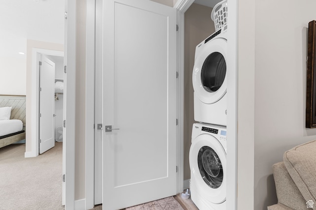 clothes washing area with stacked washer and dryer and light colored carpet