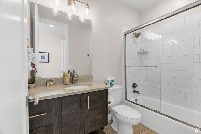 full bathroom featuring shower / bath combination with glass door, wood-type flooring, vanity, and toilet