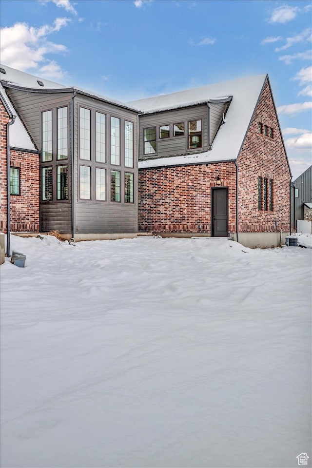 snow covered house featuring central AC unit
