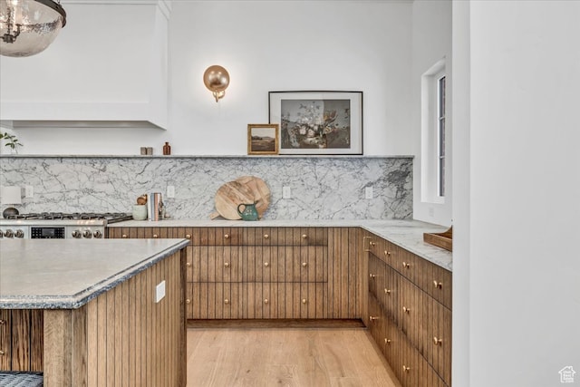 kitchen with decorative backsplash, light hardwood / wood-style flooring, and stainless steel range oven