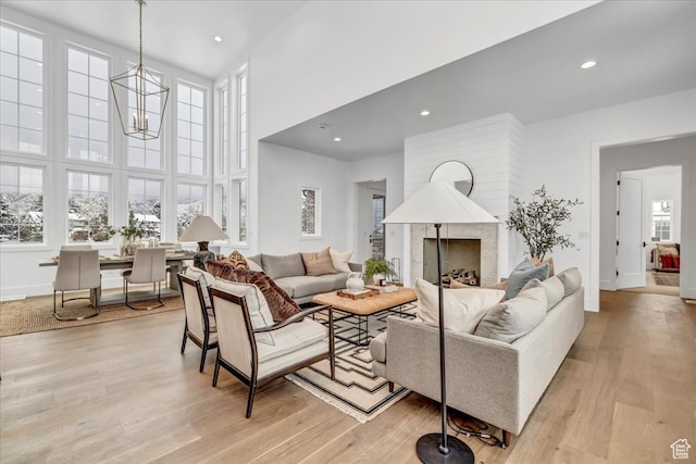 living room with a chandelier, a high ceiling, and light hardwood / wood-style floors